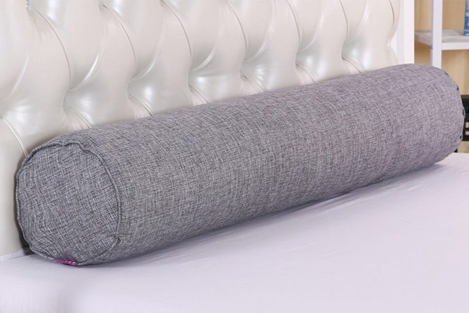 Фото удлиненной серой цилиндрической подушки-валика для кровати
